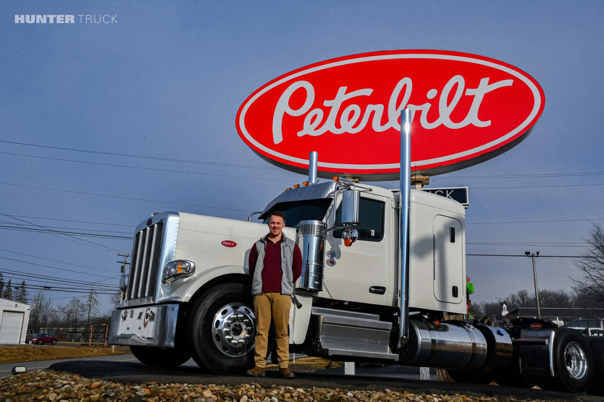 Sam Horne of Hunter Truck - Butler standing in front of red and white Peterbilt sign and truck